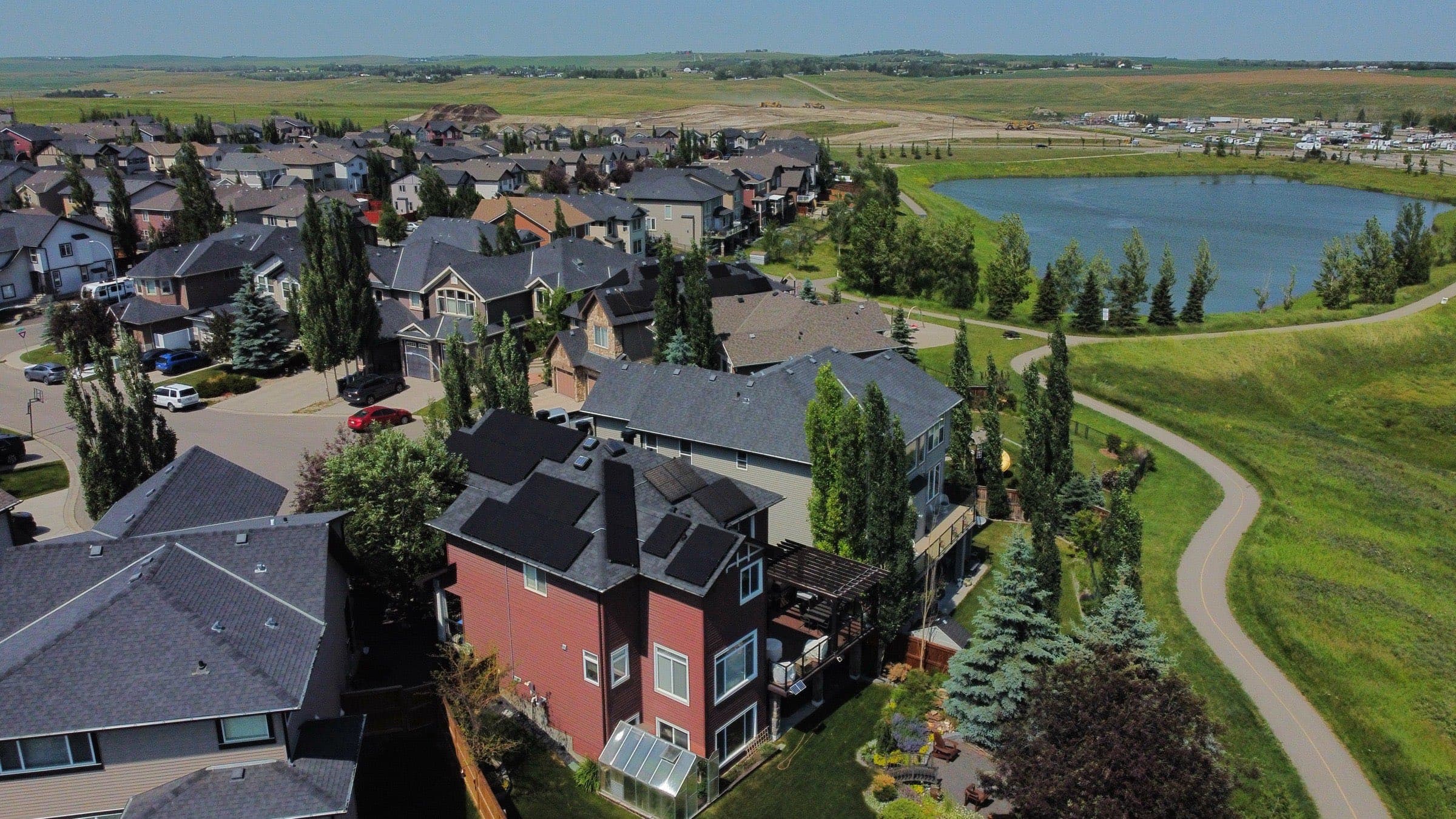 Rooftop solar array on a two-storey Calgary home, from above, with the lake behind
